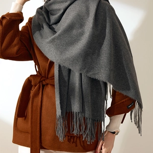 Solid dark grey cashmere-like scarf with long tassels paired with a brown wool coat
