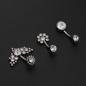 Detailed view of titanium steel belly rings with sparkling crystals on black background