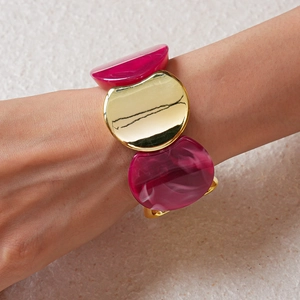 Dettaglio del bracciale elastico in acrilico e metallo dorato con trama marmorea al polso