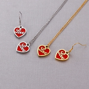 Détail de pendentifs cœur en émail rouge et gravure Love en finitions or et argent