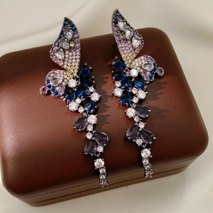 Gros plan de boucles d'oreilles papillon en zircon coloré avec pompons sur un coffret