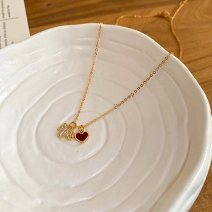 Détail du collier doré avec pendentif chiot en zircon et cœur rouge sur céramique