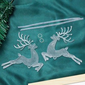 Detail of transparent Christmas reindeer ornaments with hanging ribbons on green velvet