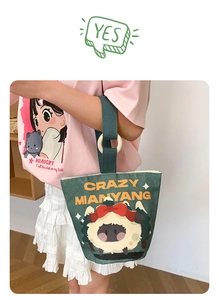 Close-up of dark green canvas bucket bag with cartoon sheep and wooden ring handle