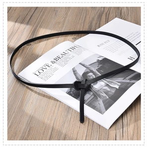 Detail of minimalist black skinny leather belt with knot closure on fashion magazine