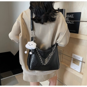 Detail of black woven shoulder bag featuring silver metal chain and fluffy cloud pendant