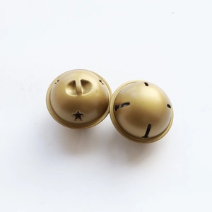 Close-up of golden metal star bells with hanging ring and cross opening for DIY crafts