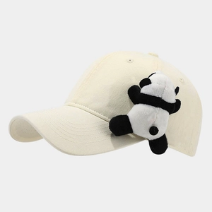Détail d'une casquette en coton blanc crème avec un petit ornement de panda en peluche