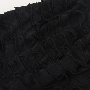 Detailed close-up of the layered black pleated fabric and ruffled textures on the beanie
