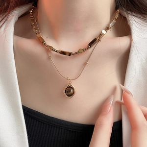 Close-up of double-layer gold plated necklace with tiger eye beads and round pendant