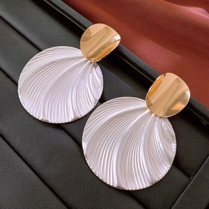 Detailed close-up of vintage round textured shell-like earrings with gold-tone accents