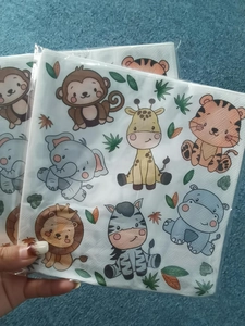 Close-up of square paper napkins with colorful cartoon jungle animal prints for parties