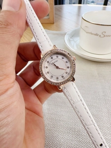 Detail of rose gold rhinestone watch with white leather strap and quilted dial pattern