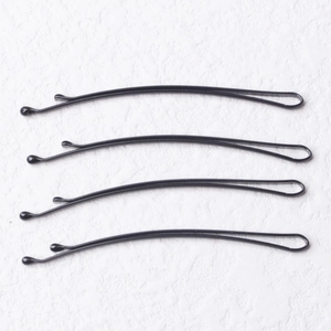 Detailed view of four black metal bobby pins with wavy design and protective round tips