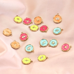 Colorful enamel star and lightning bolt charms on pink silk for jewelry making