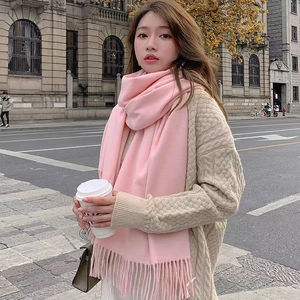 Close-up of pink cashmere-like scarf with fringe detail worn with a beige sweater