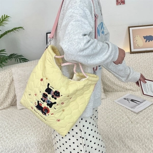 Detail of yellow quilted tote bag featuring cartoon cat embroidery and pink drawstring closure