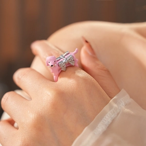Close-up of pink puppy ring with diamond-encrusted silver bow on model finger