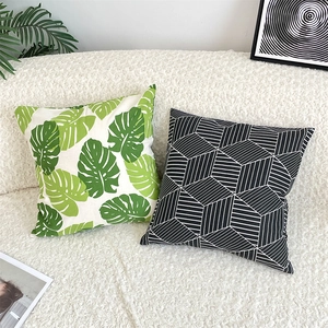 Close-up of green leaf and geometric pattern cotton linen pillow covers on white sofa