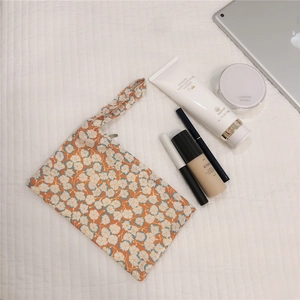 Detail of floral cotton wristlet pouch organizer for cosmetics on a textured fabric surface