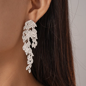 Macro shot of a sparkling silver leaf tassel earring worn by a model with detailed stones