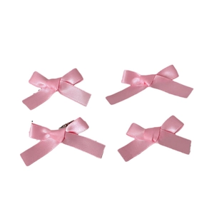 Set of four sweet pink ribbon bow hair clips in a minimalist flat lay arrangement