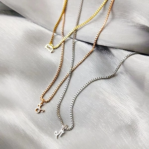 Detailed view of three-color zodiac pendant necklaces on a silk background with box chains