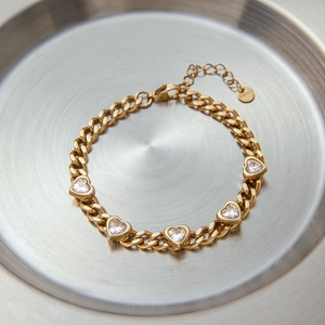 Detail of gold heart zircon bracelet with lobster clasp and extension chain on silver tray