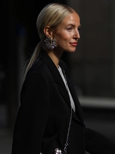 Close-up of a large sunflower-shaped earring with iridescent crystals worn by a model