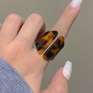 Detailed view of tortoiseshell resin ring with dual parallel geometric bands on finger