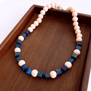 Detail of bohemian wooden beads and lapis lazuli beaded necklace on dark wood tray