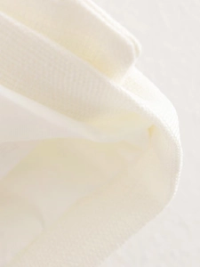 Detailed close-up of white woven fabric texture and high-quality hemmed stitching detail