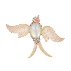 Macro shot of gold swallow brooch featuring white rhinestones and an opal-like center stone