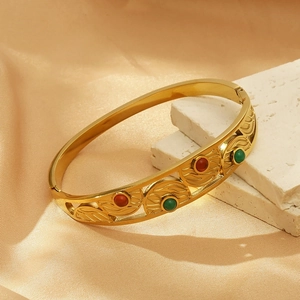 Detail of vintage gold evil eye cuff bracelet with red and green bead accents on silk