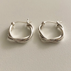 Macro shot of 925 sterling silver hoop earrings featuring a twisted metal texture design