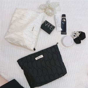 Detail view of black and white geometric jacquard makeup bags on quilted fabric