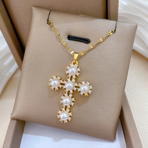 Detail of gold cross pendant with six pearls and zircon stones on a jewelry display