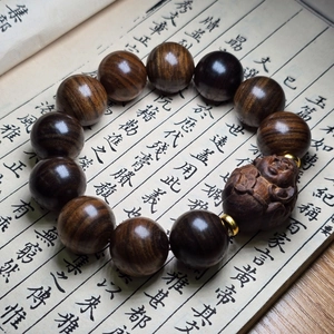 Détail de perles de prière en bois d'agar noir avec perle dorée et bête sculptée