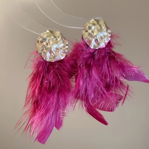 Detailed texture of gold irregular hammered discs with vibrant rose red feather tassels