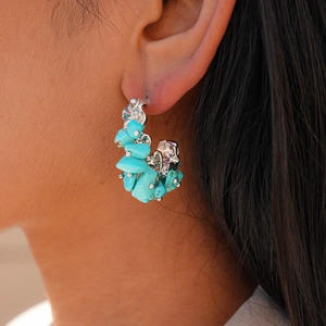 Close-up of vintage C-shaped silver earrings with inlaid irregular turquoise stones