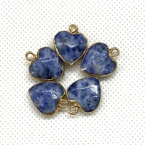 Macro view of blue heart stone pendants with gold bezels on a white textured background