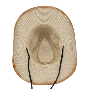Détail d'un chapeau de cowboy en paille beige avec bords usés et mentonnière noire