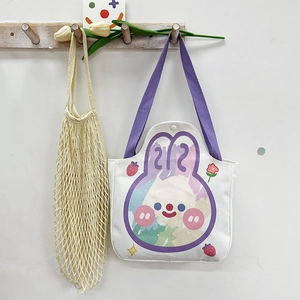 Detail of canvas tote bag featuring purple straps and a cartoon rabbit print design