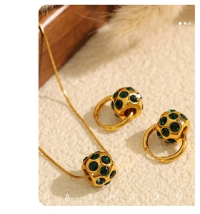 Détail d'un ensemble collier et boucles d'oreilles dorés avec cristaux verts