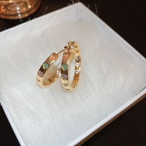 Detailed macro view of gold hoop earrings with multi-color zircon heart engravings