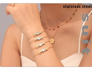 Detail shot of four-piece gold layered MAM charm bracelets with heart cubic zirconia
