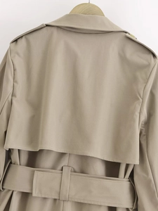 Detailed back view of khaki trench coat showing storm flap, epaulettes, and belted waistline