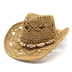Détail d'un chapeau de cowboy en paille avec bande décorative en coquillages et perles