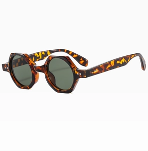 Detail of tortoiseshell hexagonal sunglasses with dark green lenses and double metal rivets