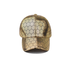Detail of golden baseball cap featuring a black hexagonal honeycomb mesh pattern texture